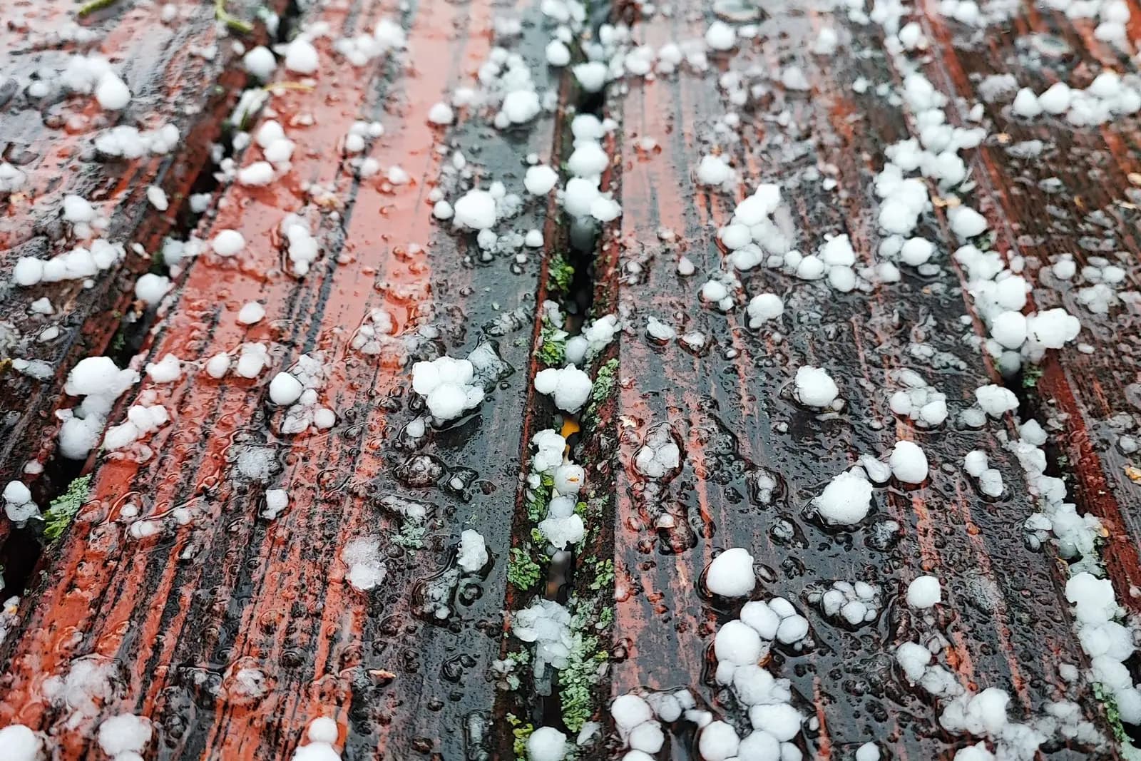Hailstones covering a wooden surface after a storm