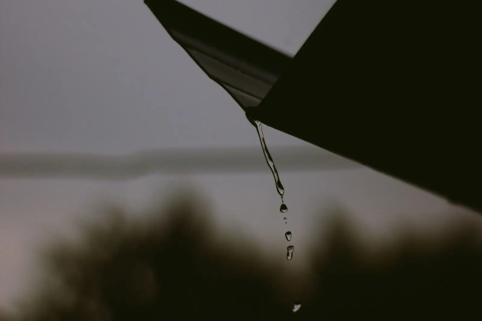 Rainwater dripping from the edge of a roof